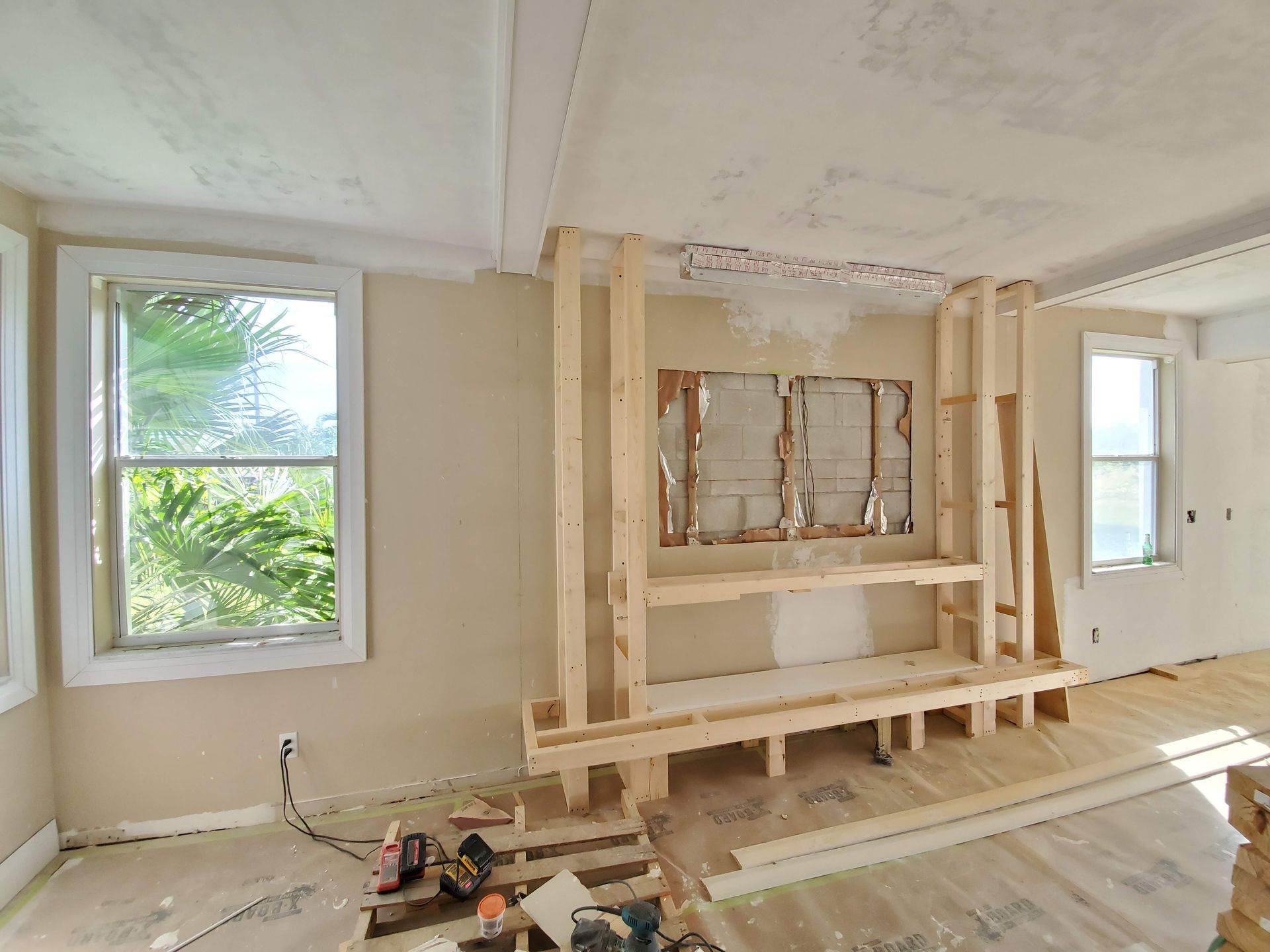 A living room under construction with wooden shelves and a window.