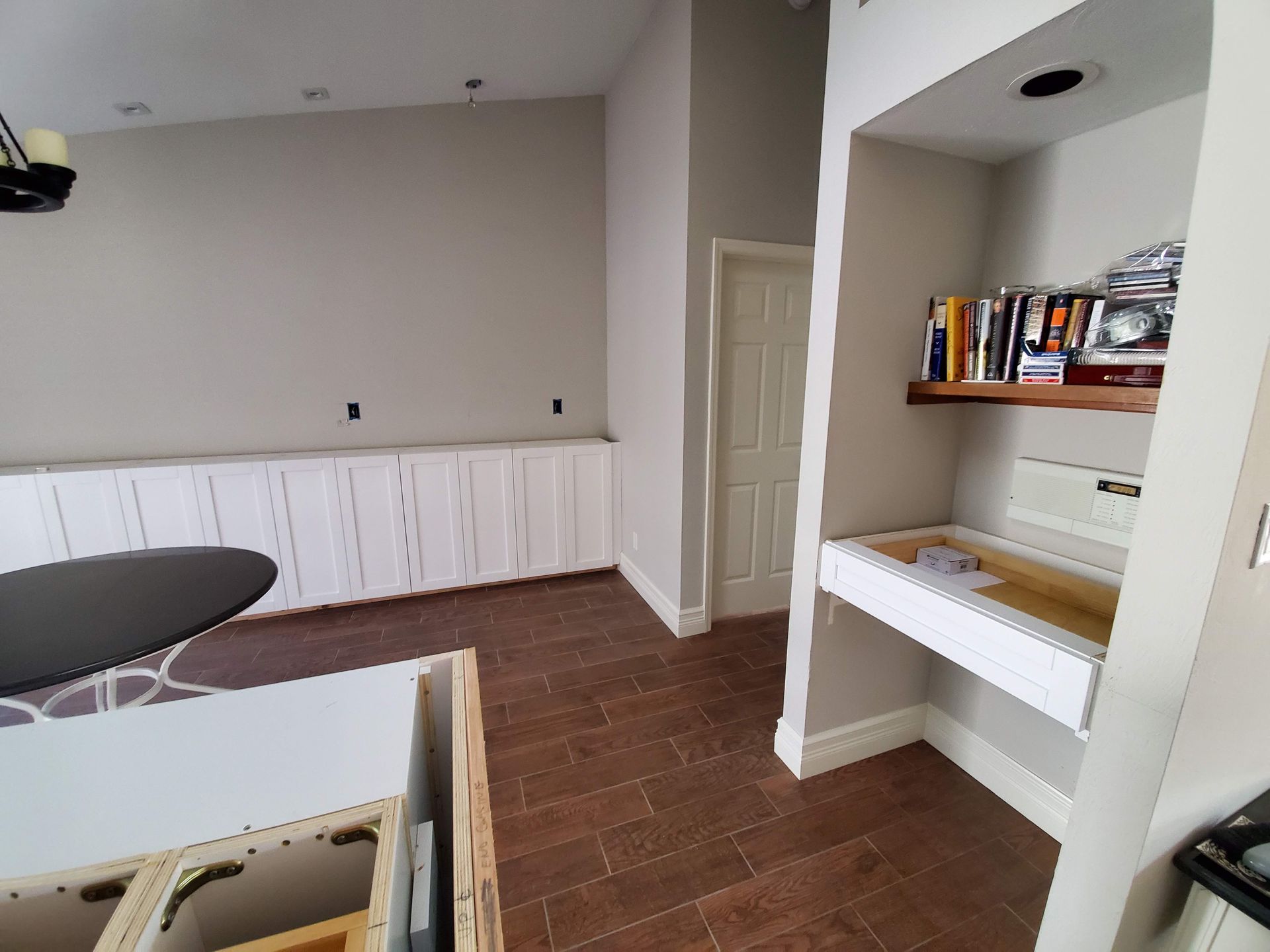 A room with a table and a shelf with books on it.