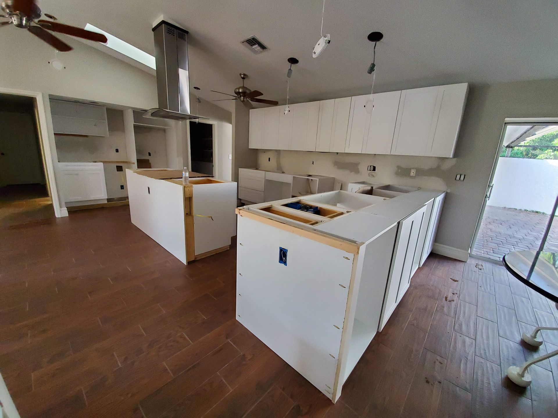 A kitchen under construction with two islands and a ceiling fan.