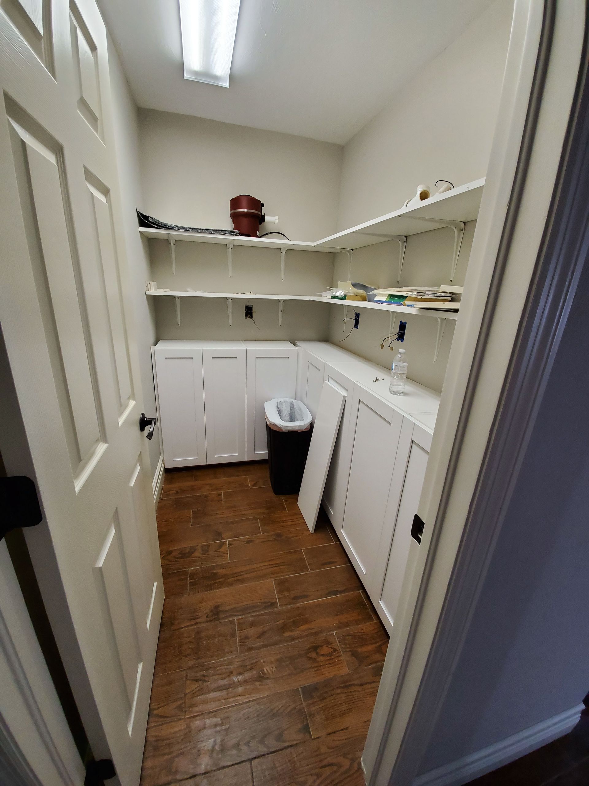 A laundry room with a washer and dryer and a trash can.