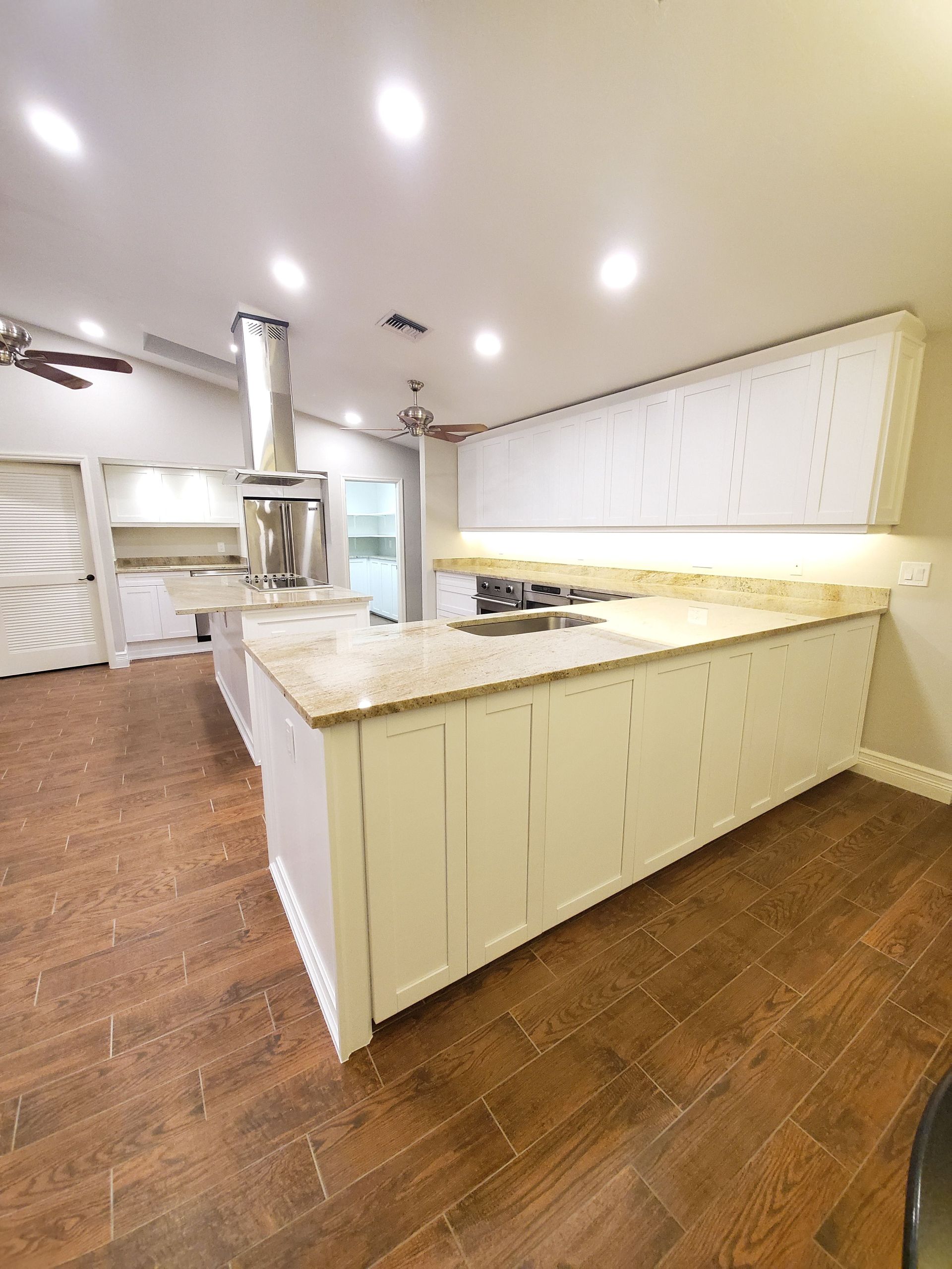A kitchen with white cabinets , granite counter tops , and a large island.