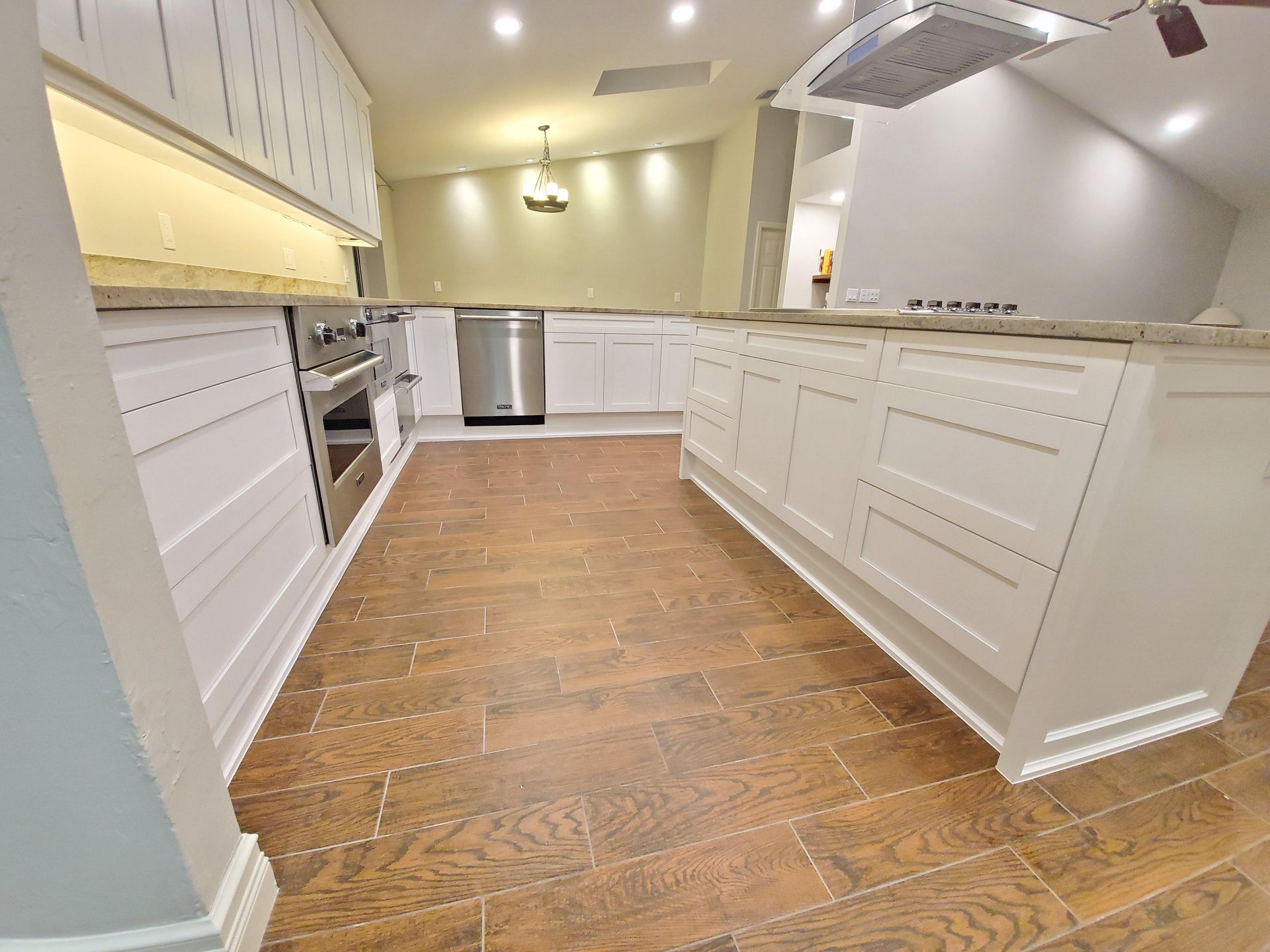 A kitchen with white cabinets and wooden floors