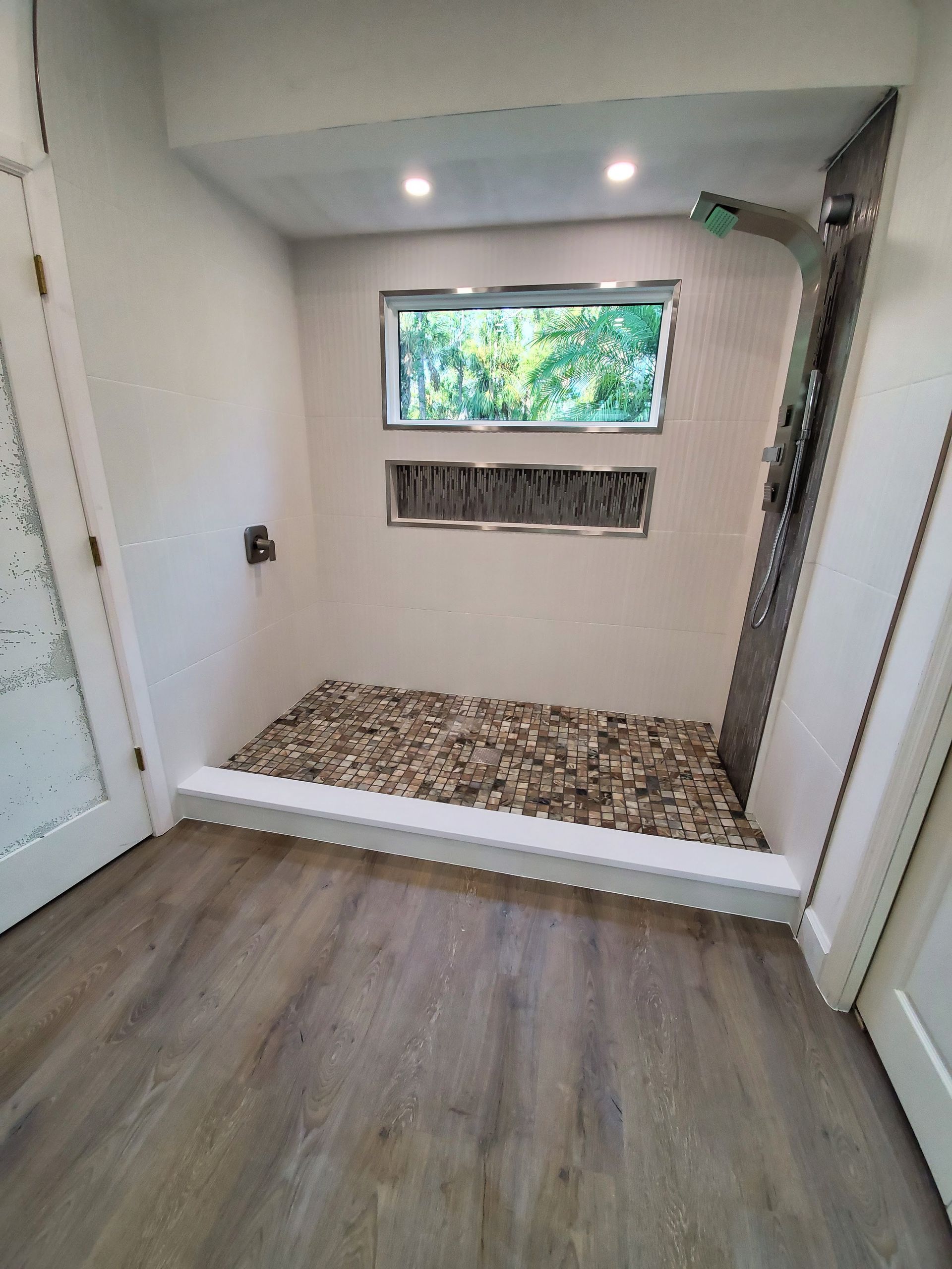 A bathroom with a walk in shower and a window.