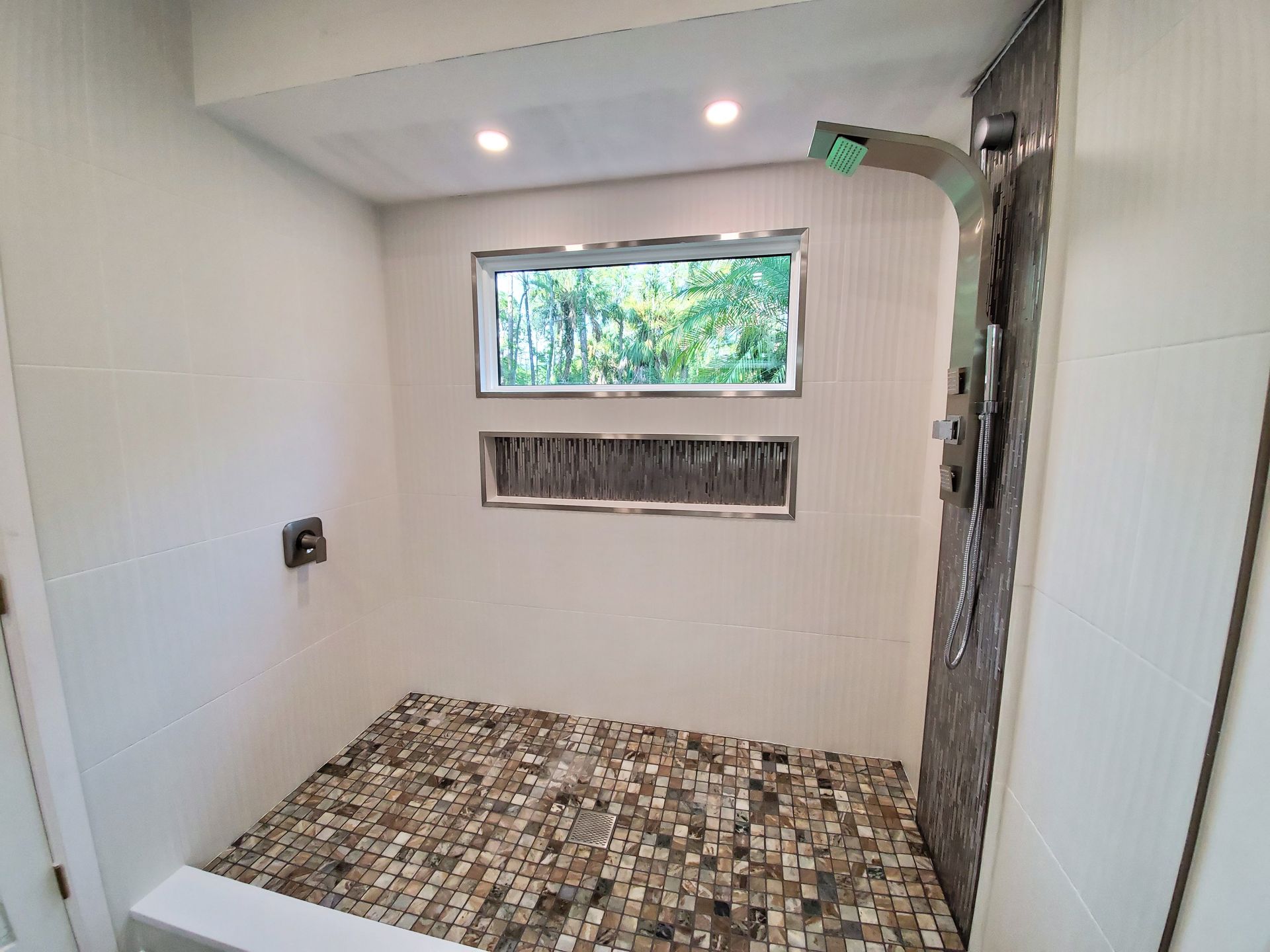 A bathroom with a walk in shower and a window.