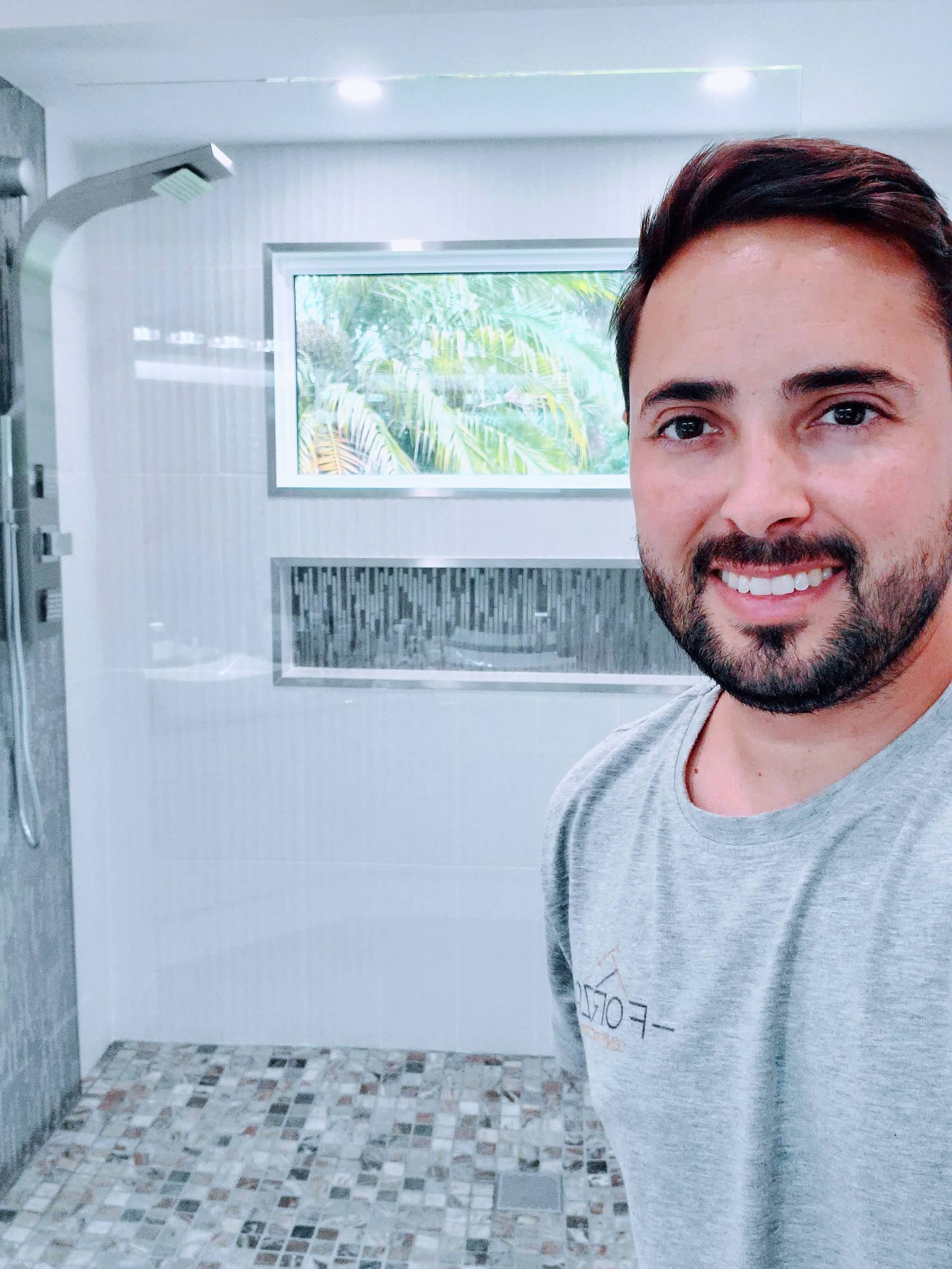 A man with a beard is taking a selfie in a bathroom.