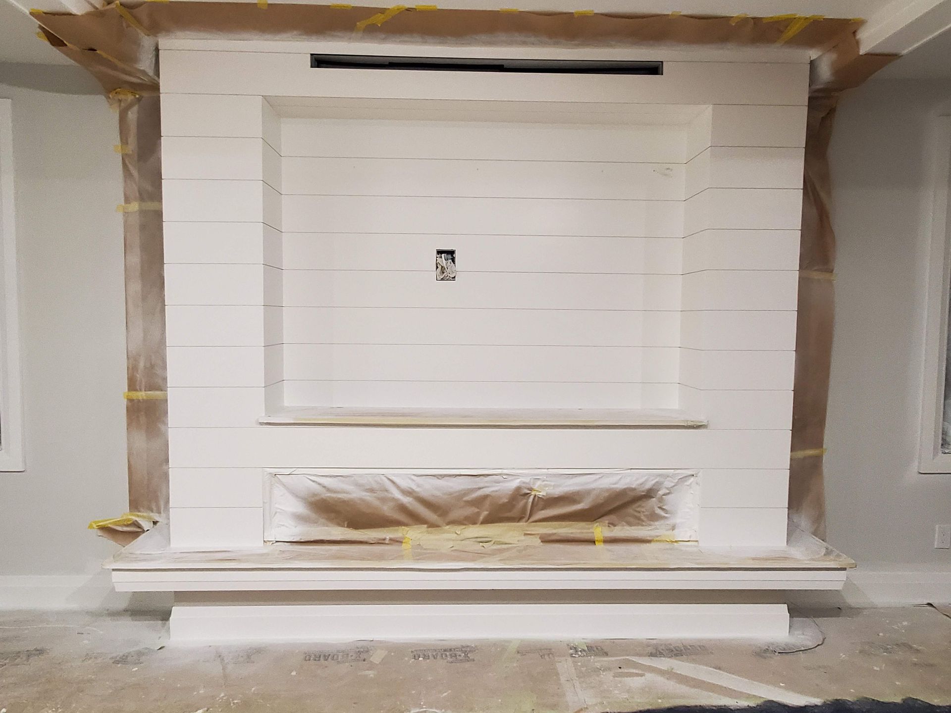 A fireplace is being painted in a living room.