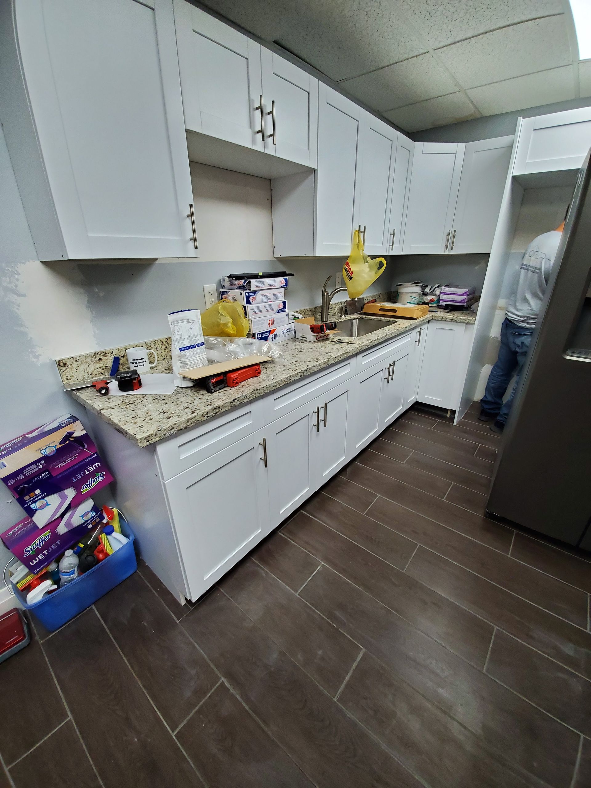 A kitchen with white cabinets and granite counter tops.