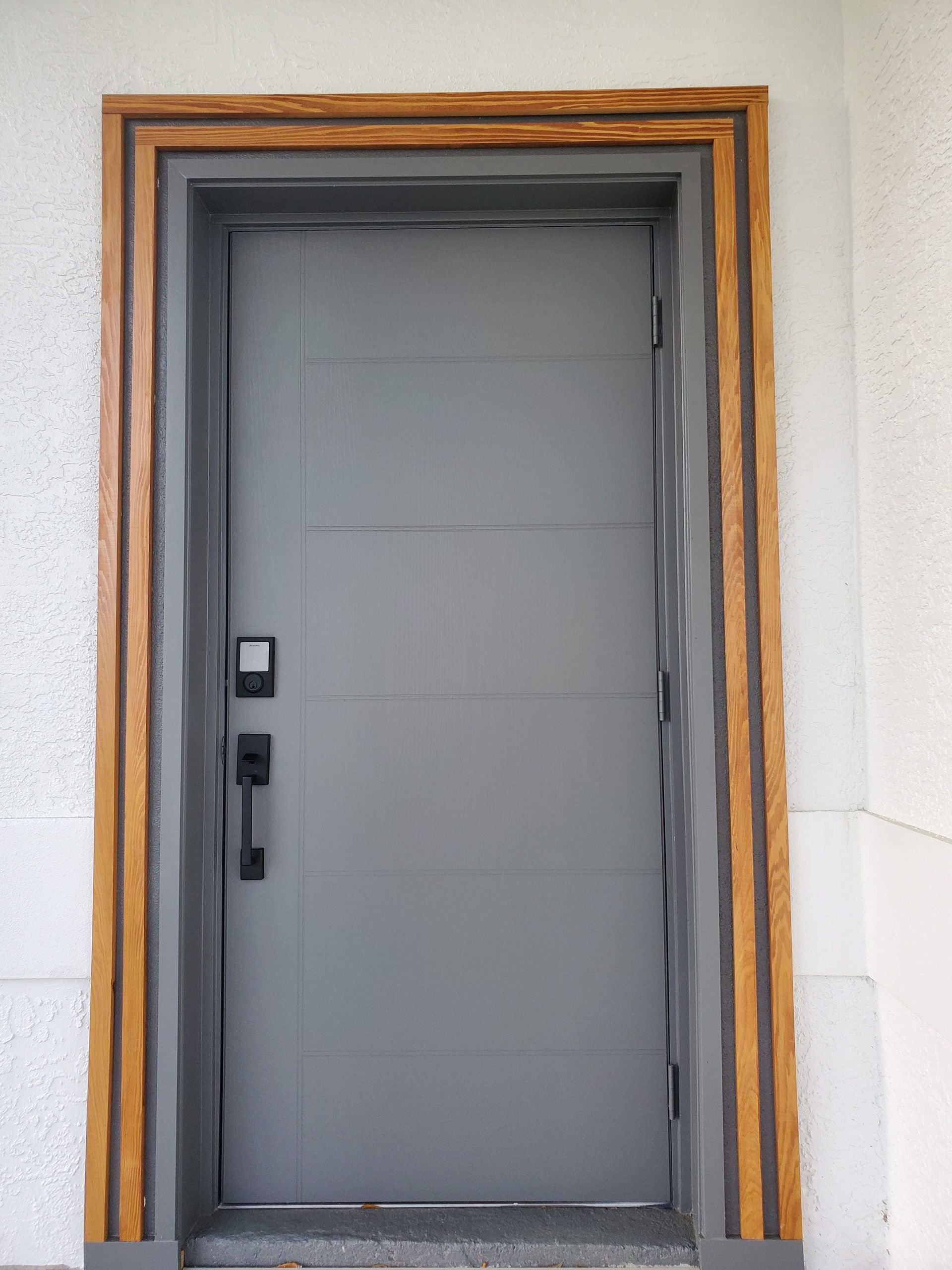 A gray door with a wooden frame on a white wall