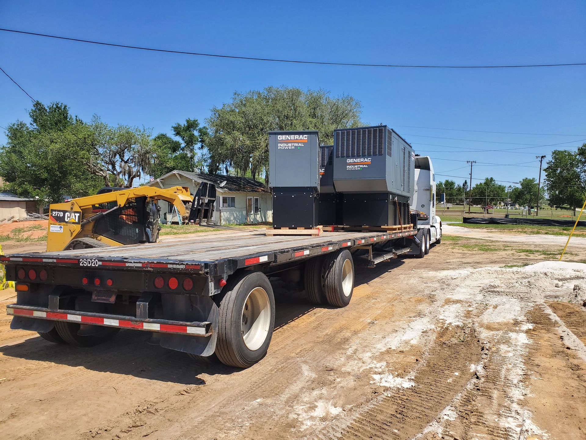 A flatbed truck is being towed by a bulldozer.