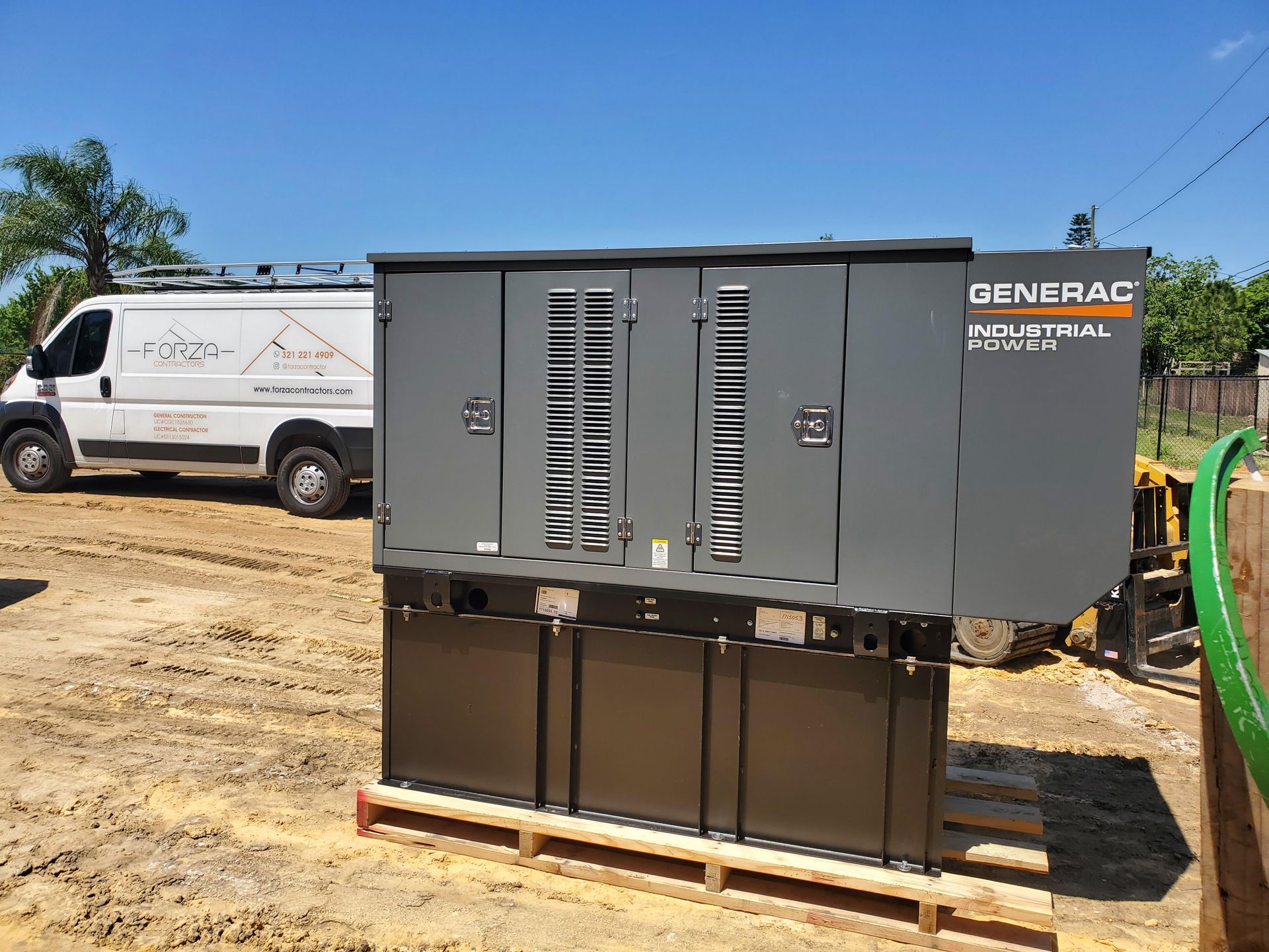 A generator is sitting on a wooden pallet next to a van.