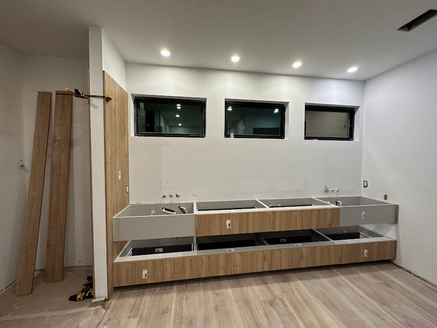 A kitchen under construction with wooden cabinets and white walls.