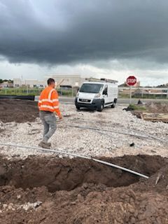 A man is standing in the dirt next to a stop sign and a van.