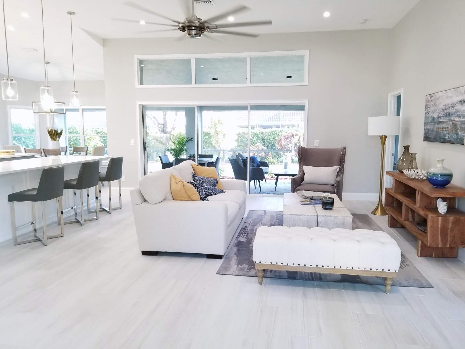 A living room with white furniture and a ceiling fan