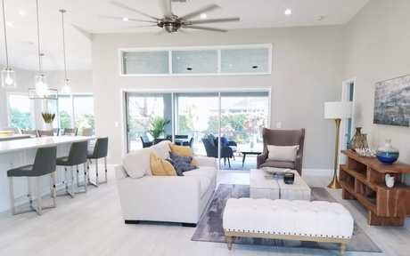 Bright, open living room with white furniture, a dining area, and sliding glass doors to a patio
