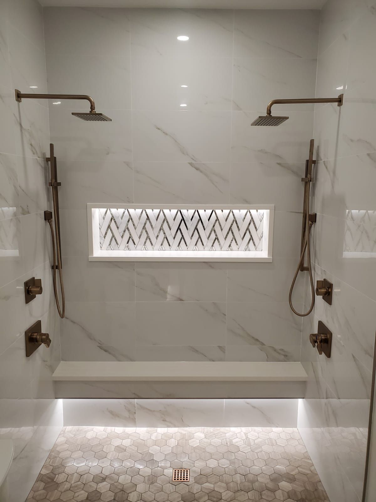 A bathroom with two showers and a bench.
