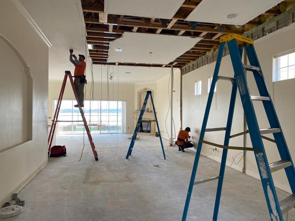 A man is standing on a ladder in an empty room.