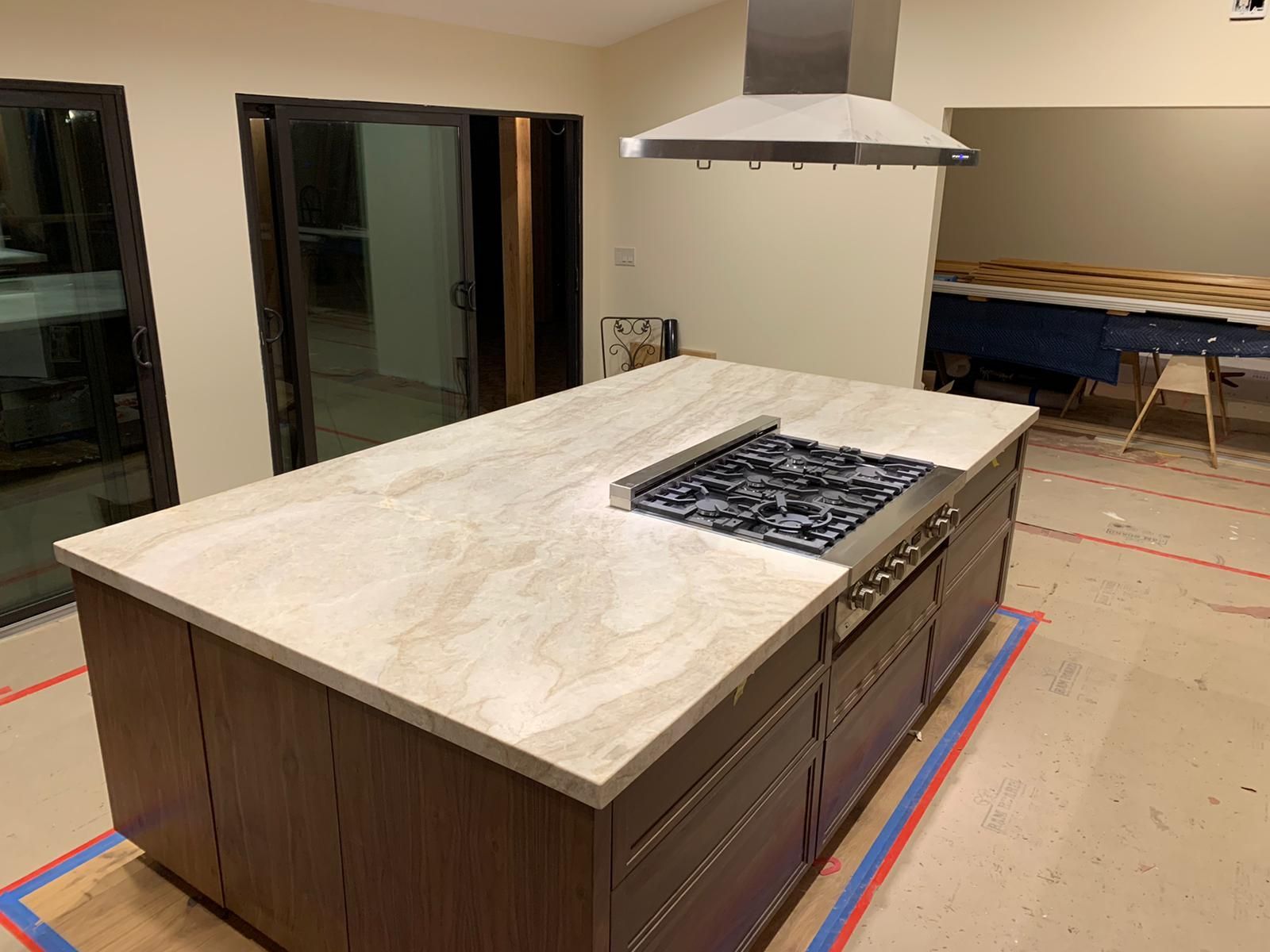 A kitchen with a large island and a stove top oven.