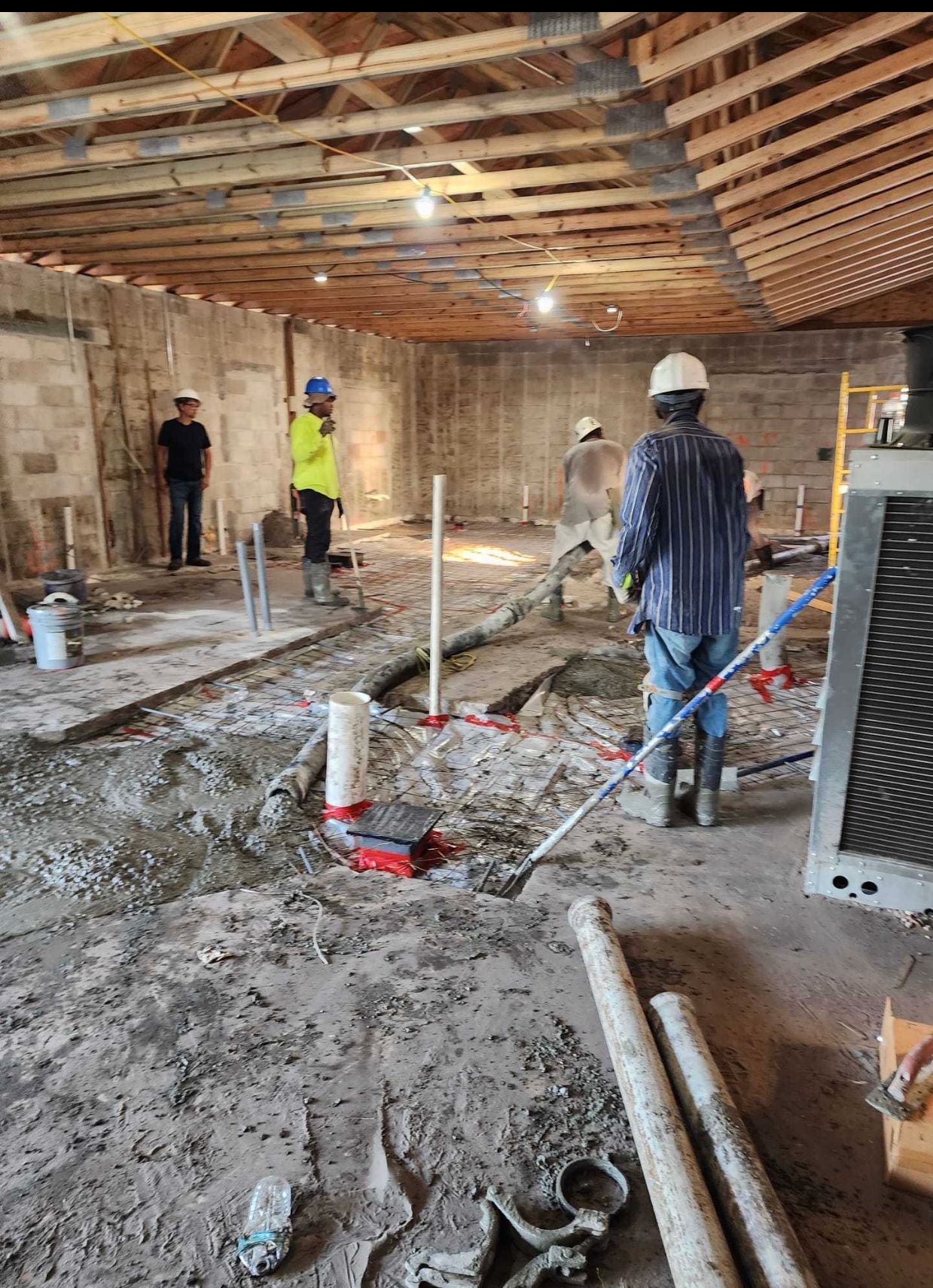 A group of construction workers are working on the floor of a building.