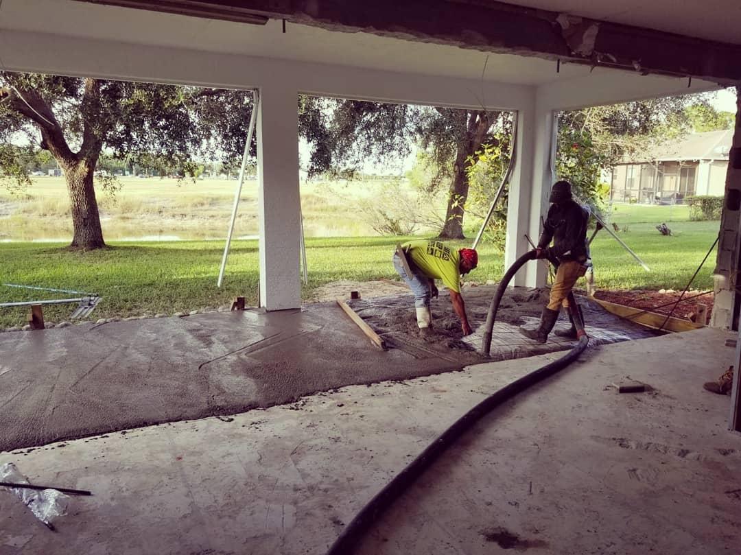 Two men are working on a concrete floor in a garage.