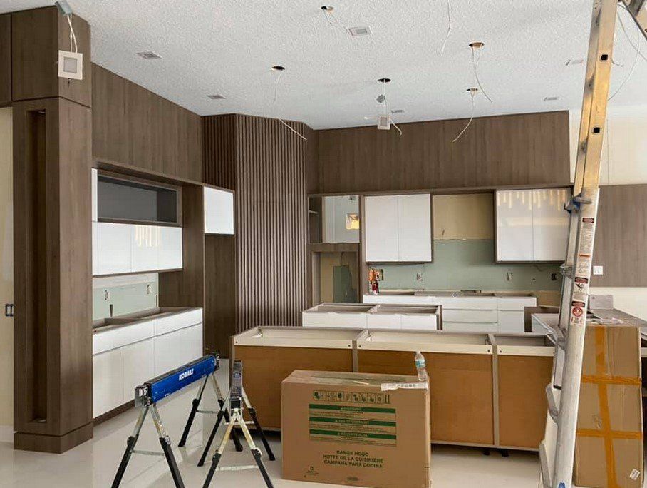 A kitchen is being remodeled and a cardboard box is sitting in the middle of the room.