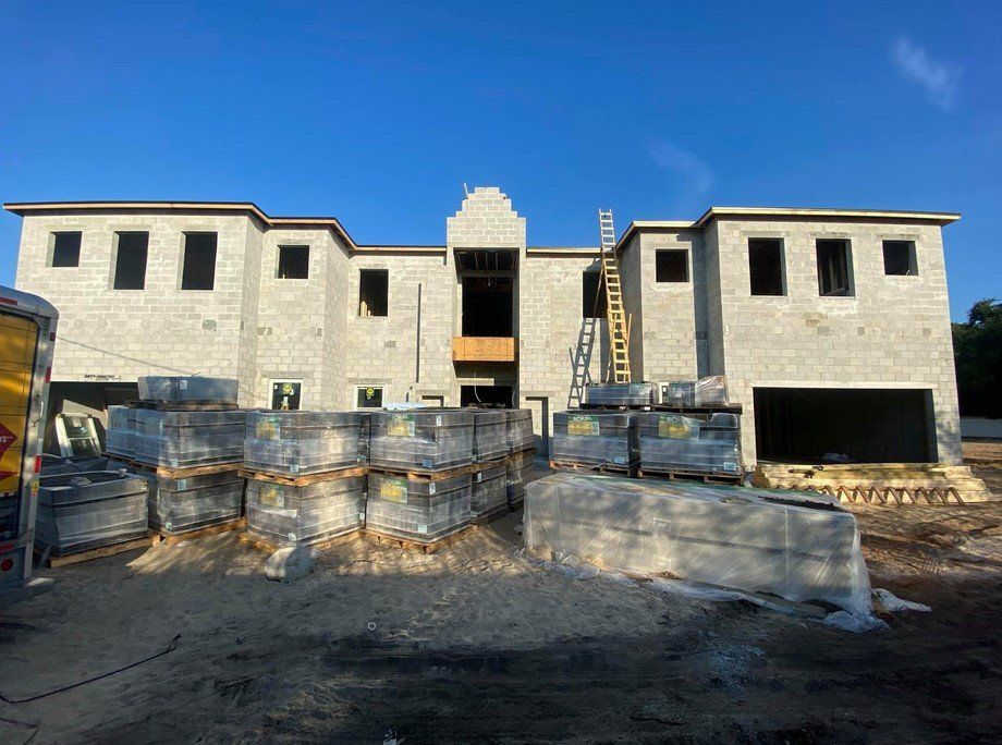 A large brick house is being built in the middle of a dirt field.