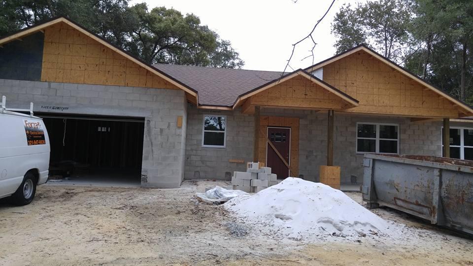 A white van is parked in front of a house under construction