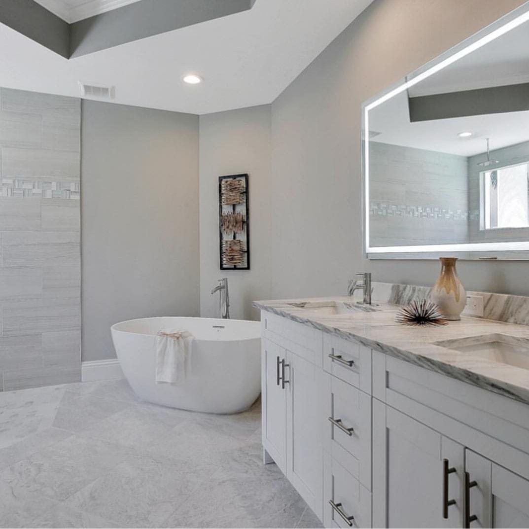 A bathroom with a bathtub , sinks , and a large mirror.