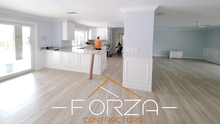 A large empty room with a forza contractors logo on the wall.