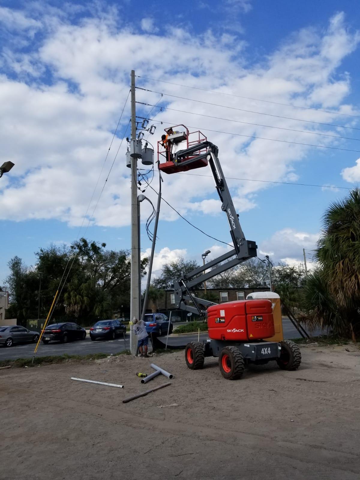 A man is working on a power pole with a crane.