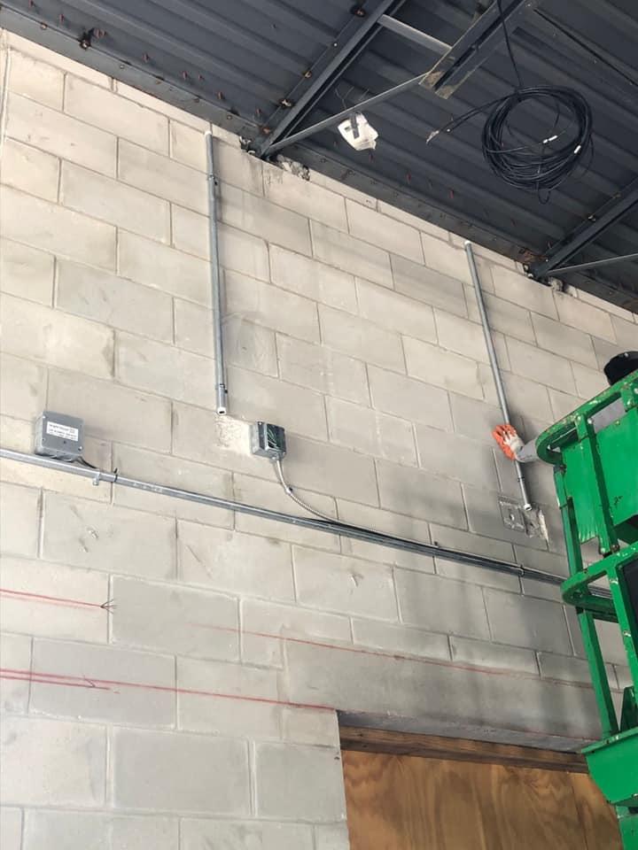 A person in a green lift is working on a brick wall.
