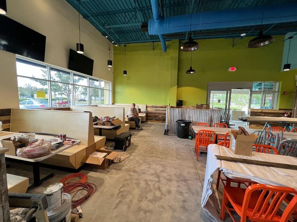 The inside of a restaurant under construction with tables and chairs.