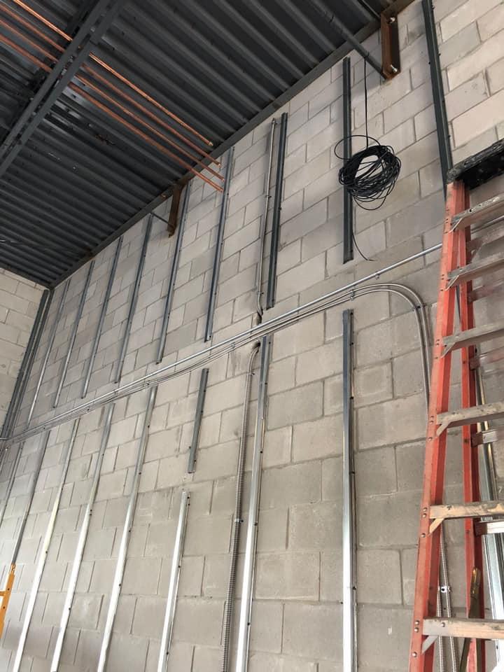 A ladder is hanging from the ceiling of a building next to a brick wall.