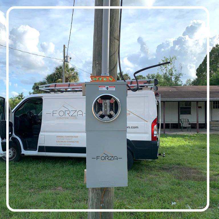 A forza van is parked next to a power box on a pole.