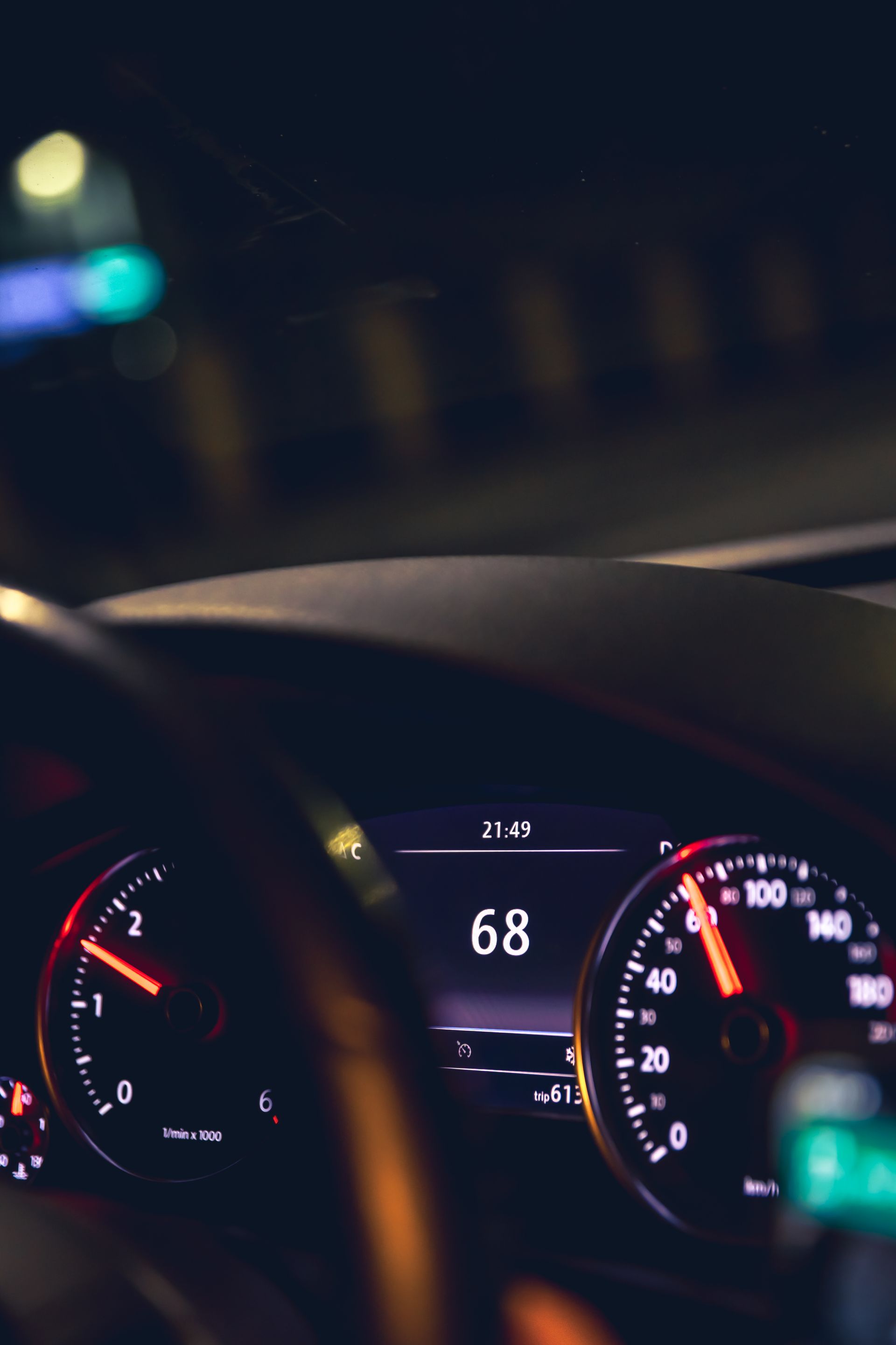 Car dashboard at night showing 68 mph on a lit speedometer and digital display