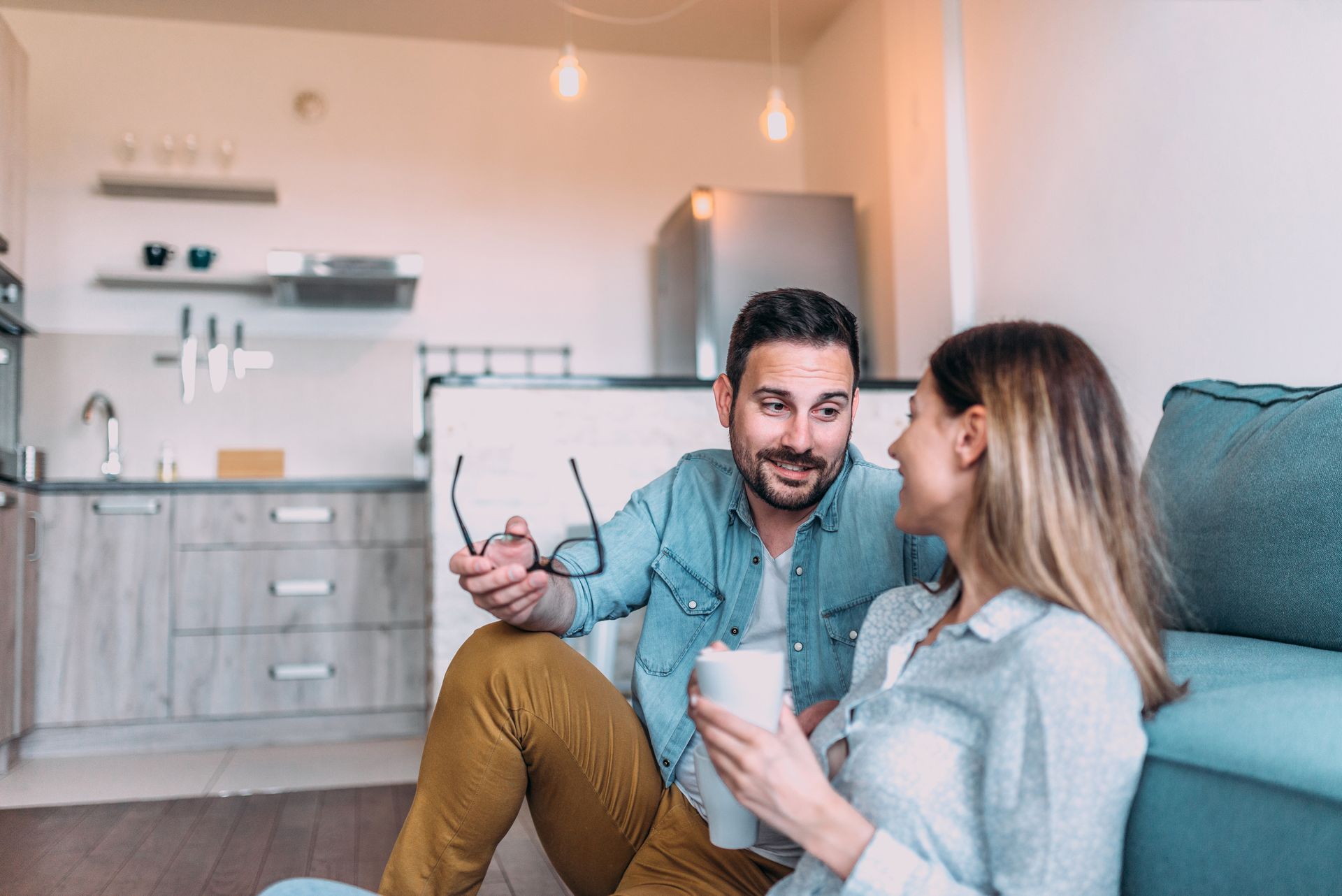 Two people chatting on a couch in a bright modern apartment kitchen-living room