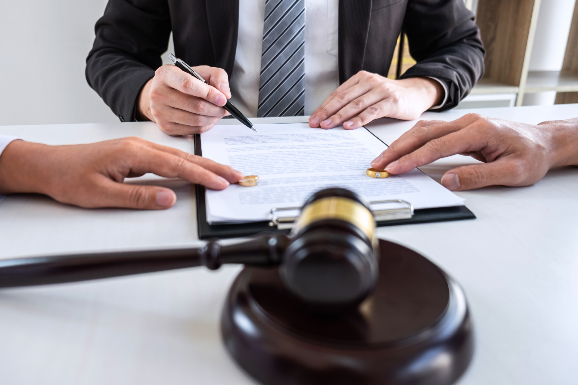 Lawyer signing legal documents with a gavel in the foreground during a meeting