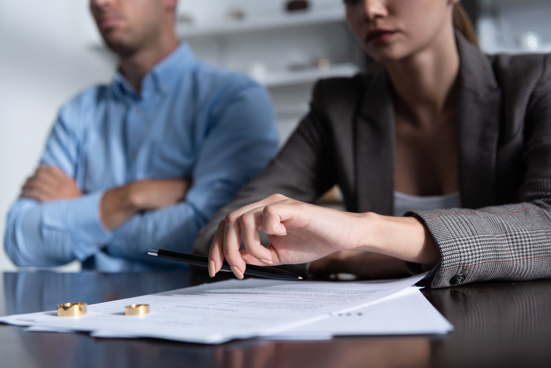 People in a meeting reviewing documents at a conference table, with one hand resting on papers and a pen nearby