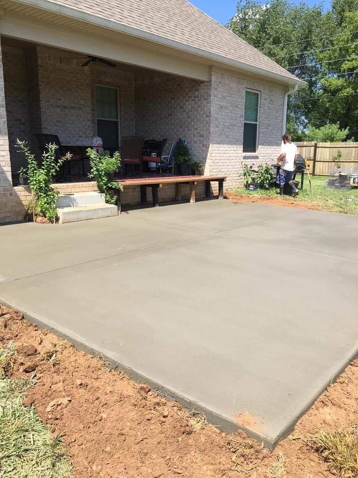 Fresh concrete driveway beside a brick house with porch seating and plants