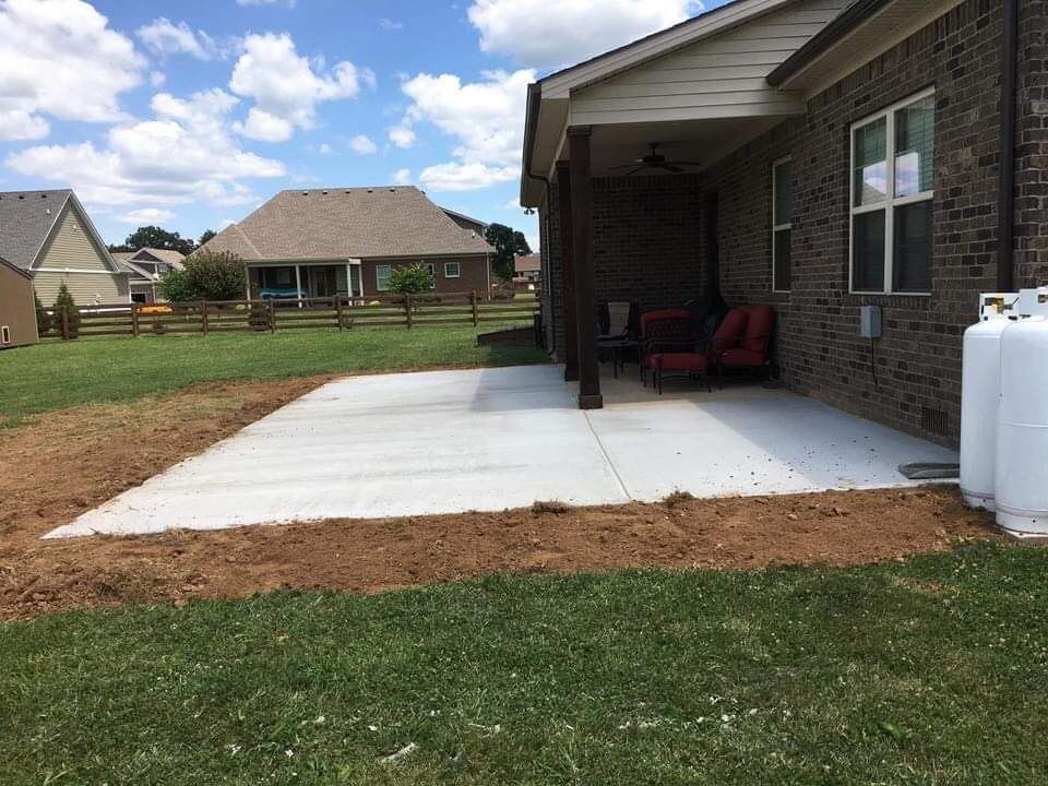 Concrete patio beside brick house with covered seating area and white propane tank in a suburban yard
