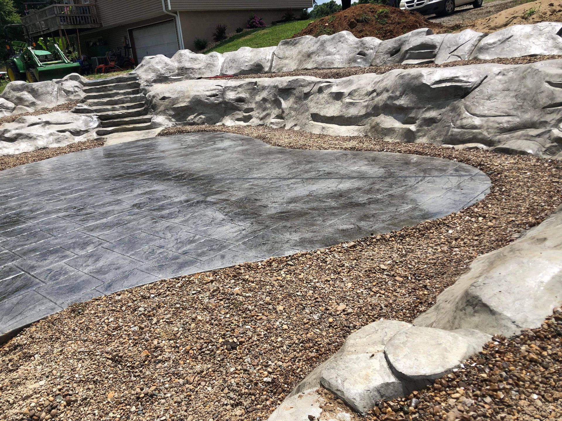 Landscaped outdoor area with a curved stone path, gravel border, and tiered rock wall seating