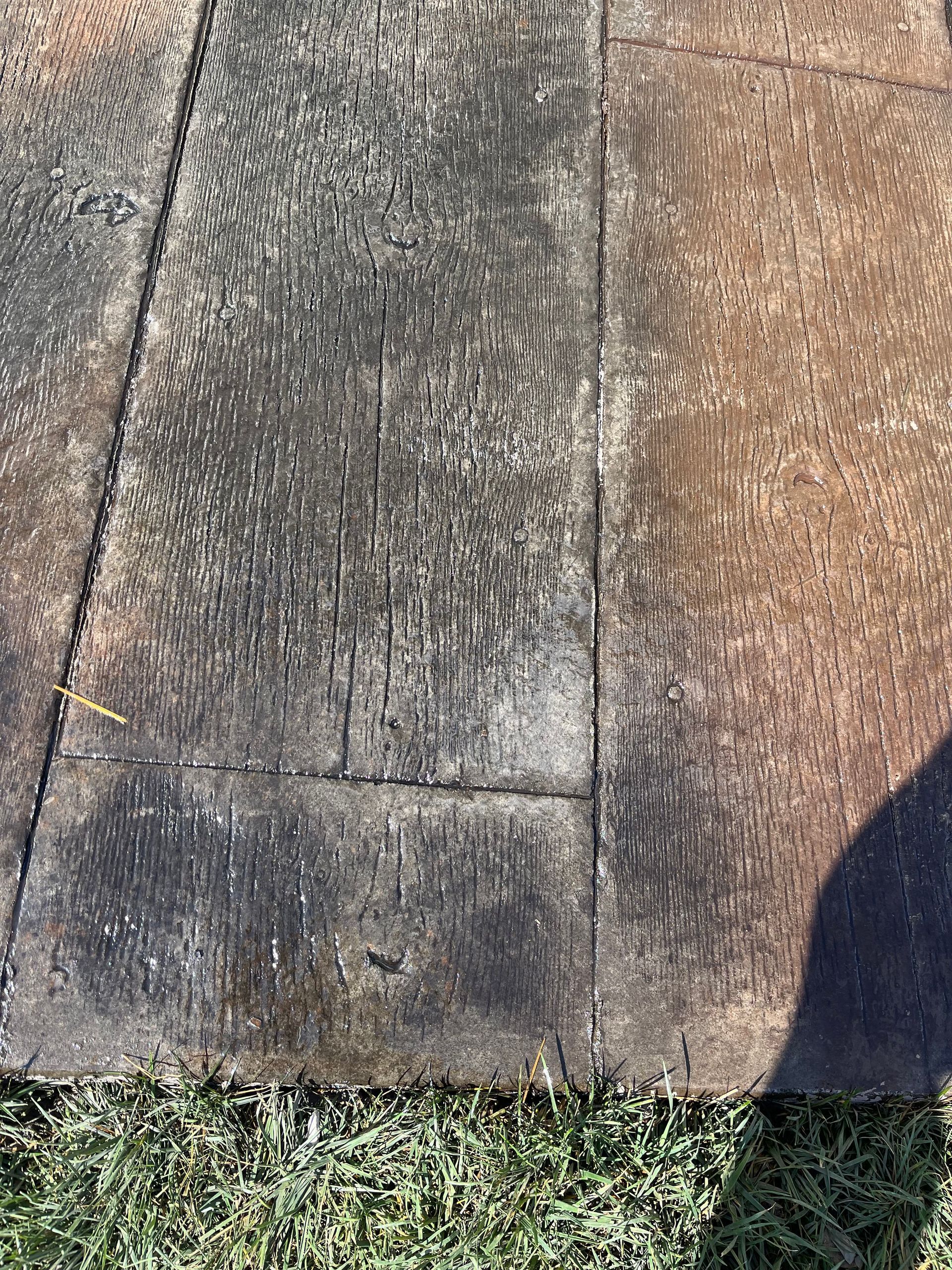 Close-up of a weathered concrete sidewalk with grass along the bottom edge.