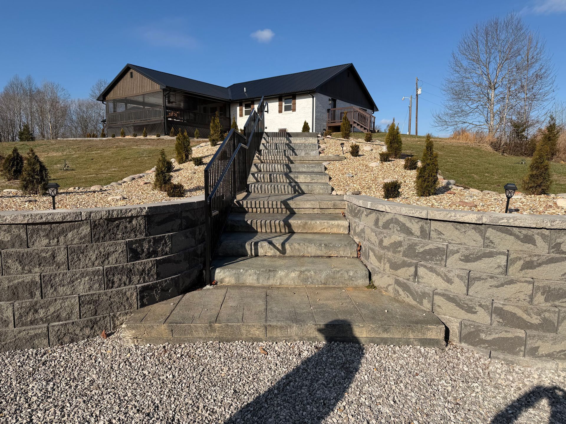 Stone steps leading up to a house on a sunny hill under a clear blue sky.