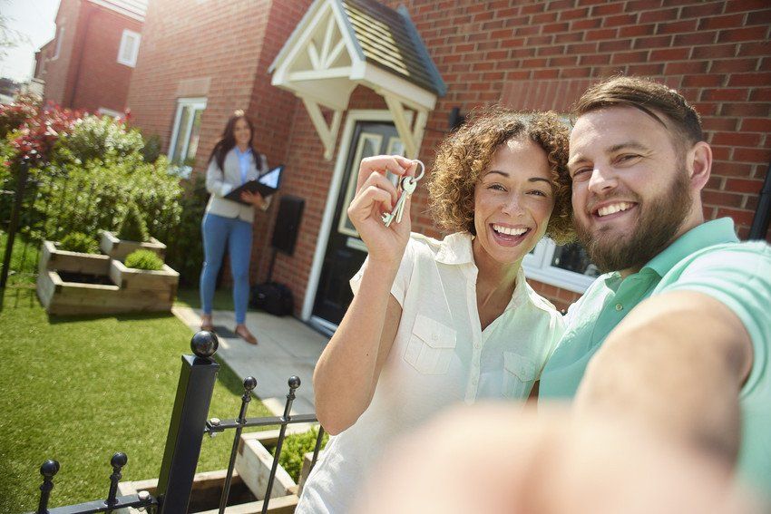 Happy couple holding up key outside new home