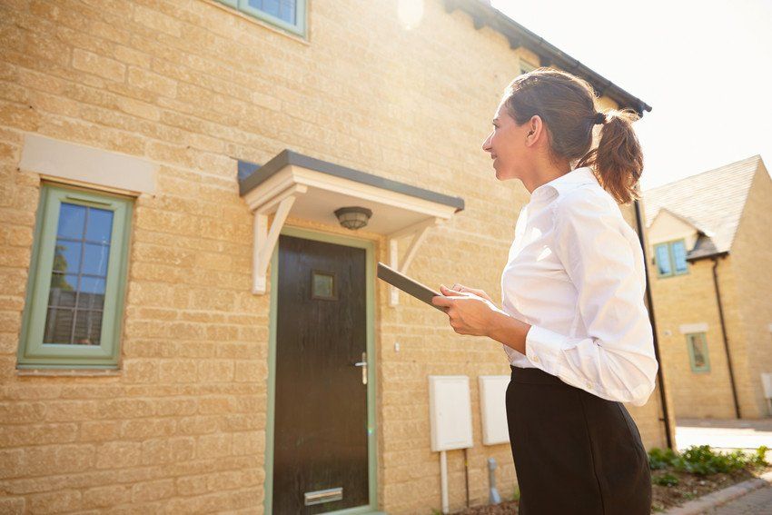 Female estate agent looking at outside of house