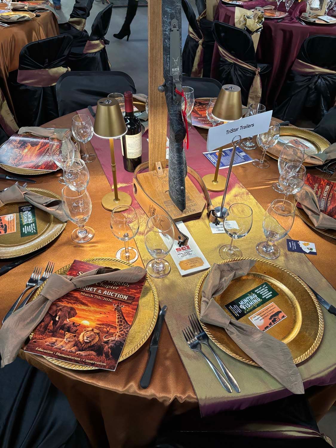 Decorated banquet table with gold plates, red napkins, glassware, and a center centerpiece