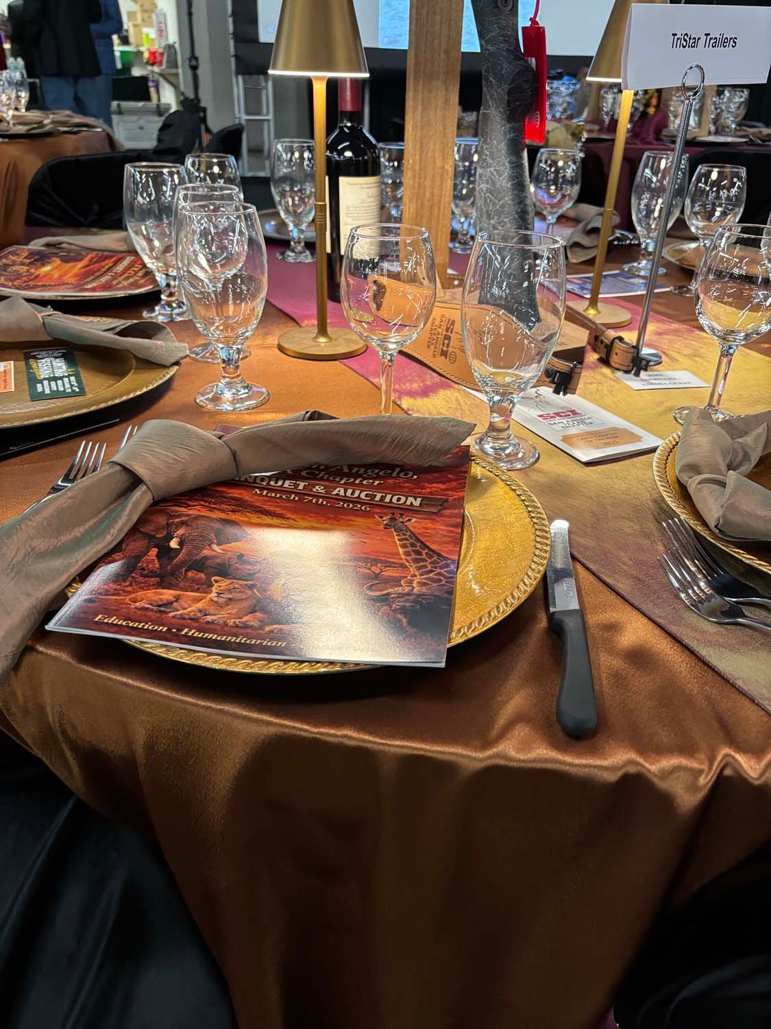 Elegant table setting with gold tablecloth, crystal glasses, and lantern centerpiece at a formal event