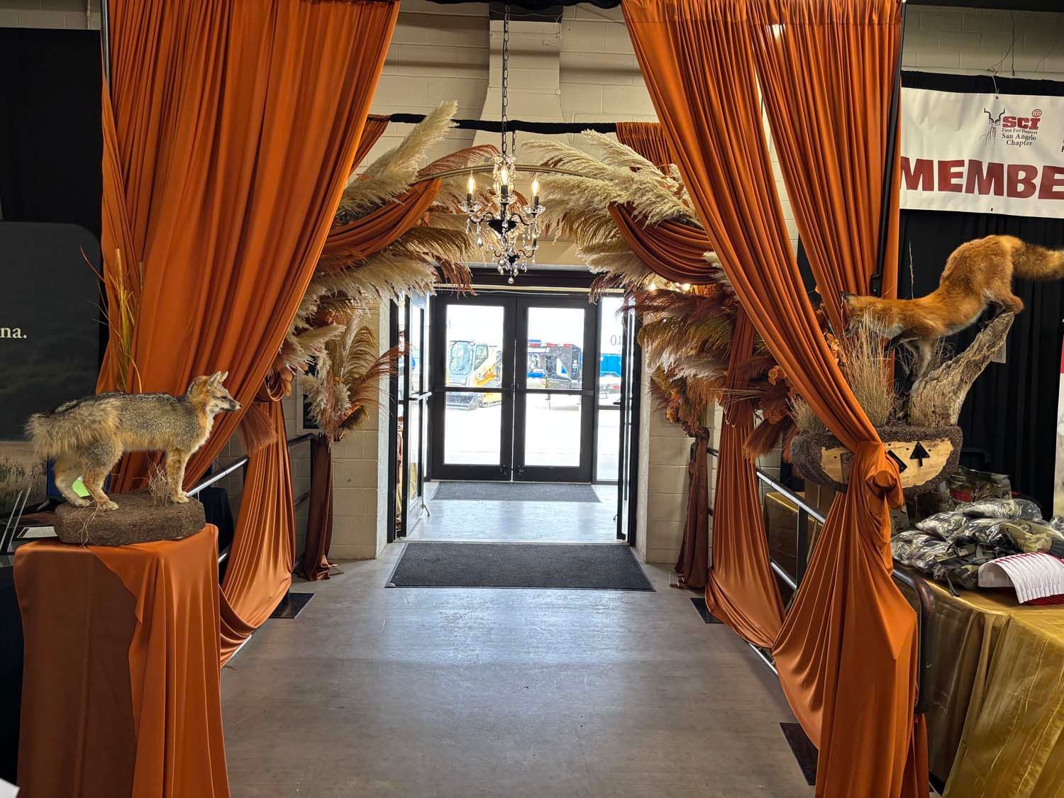 Orange drapes frame a decorated entrance with fox statues and a chandelier in a hotel lobby.