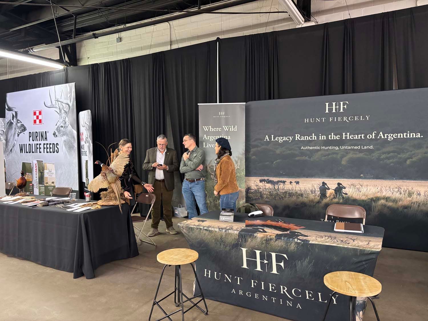 Trade show booth for HFF, with staff talking beside a branded table and black curtains backdrop.