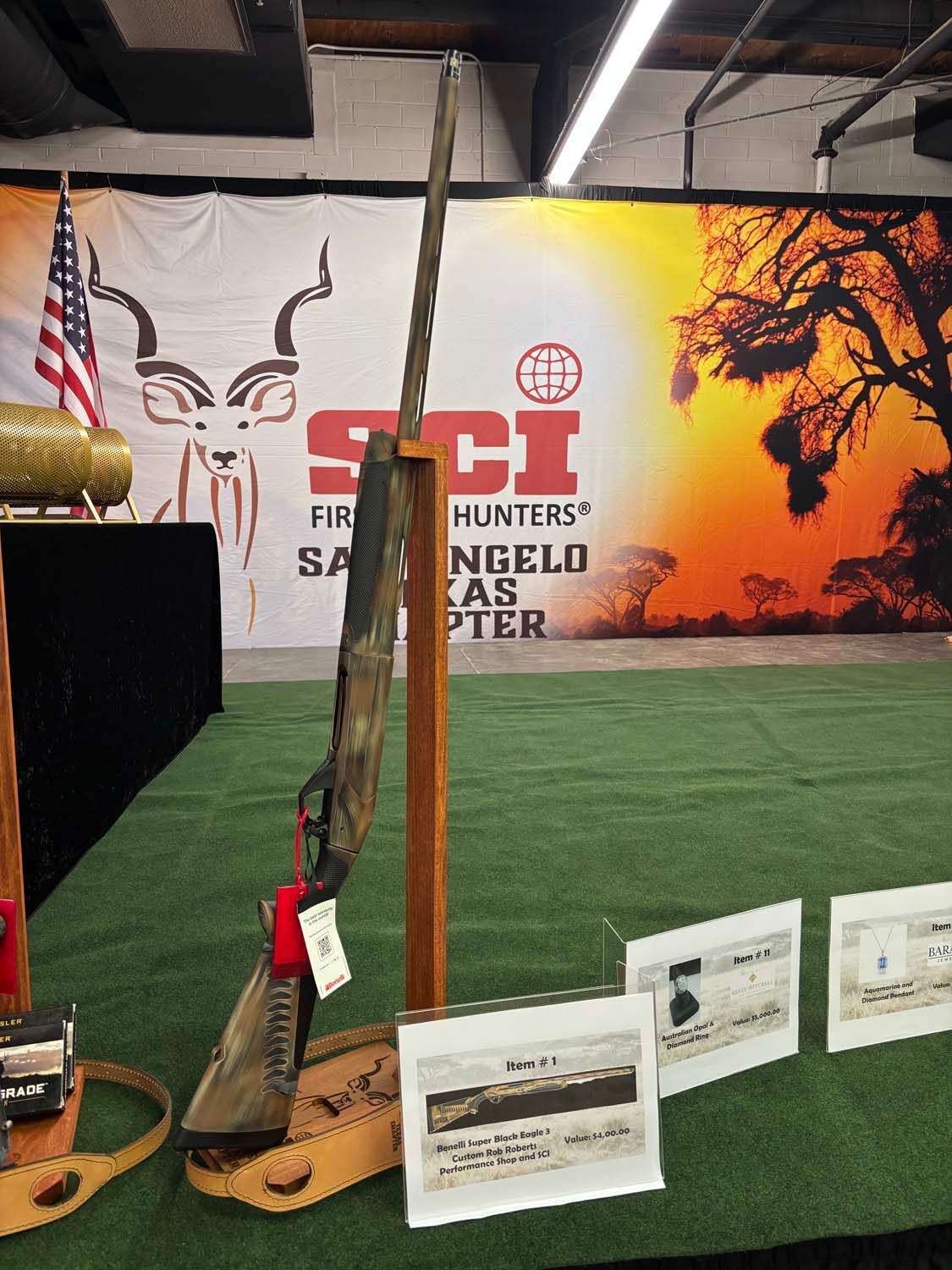 Gun exhibit booth with rifles, holsters, and informational signs on artificial turf