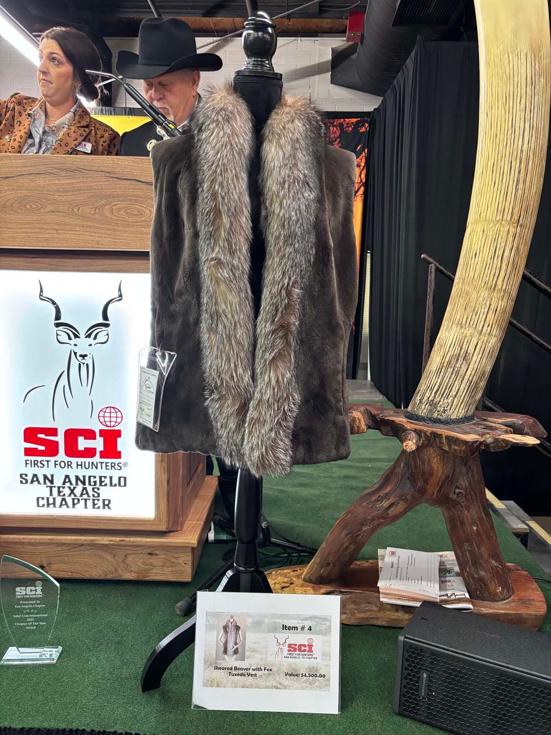 Mounted furs and taxidermy display on stands with a SCI sign at an indoor expo booth